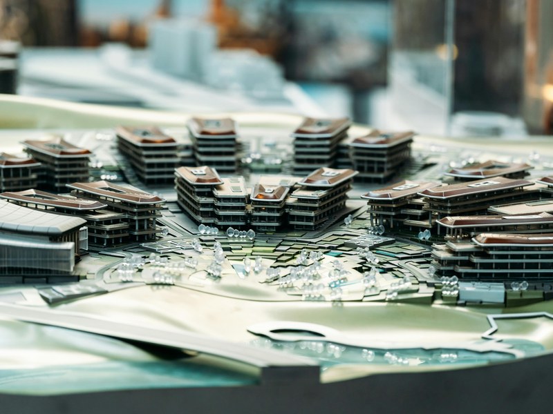 Maqueta arquitectónica y planos sobre la mesa de planeación